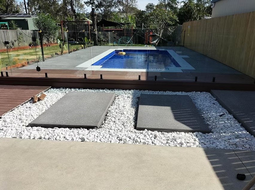 Concrete pool surround with floating stepping pads and white pebbles